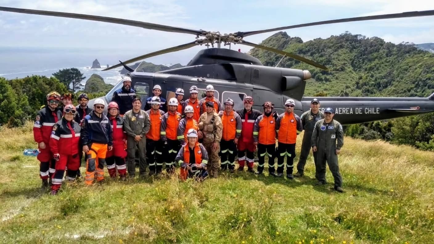 Rescatistas de USAR Ñuble junto a un helicóptero de la Fuerza Aérea de Chile en la costa